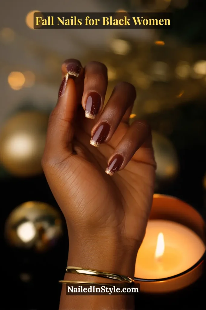 Fall nails for Black women featuring cinnamon brown nails with glittery tips, styled against a glowing holiday candle background.