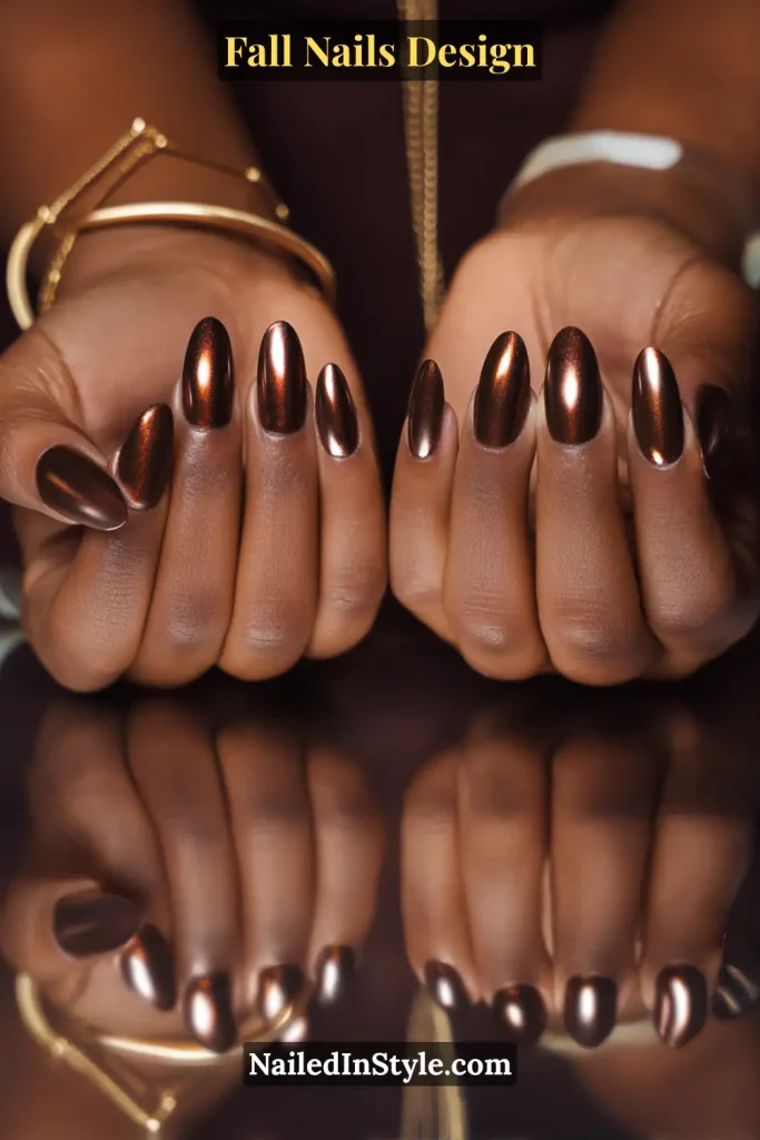 Fall Nails Design: Bold, Chic & Gorgeous Ideas 10 Fall nails design featuring bronze chrome almond nails with a reflective metallic finish, styled with jewelry for an elegant autumn look.