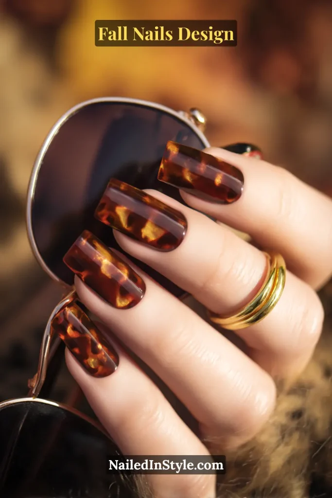 Fall Nails Design: Bold, Chic & Gorgeous Ideas 17 Fall nails design in chestnut tortoiseshell pattern with brown and caramel layered swirls, styled holding sunglasses.