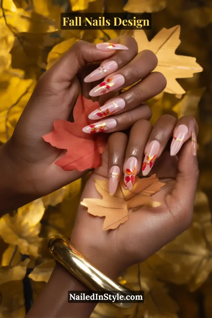 Fall Nails Design: Bold, Chic & Gorgeous Ideas 20 Fall nails design featuring a nude base with maple leaf decals in red, orange, and gold, styled while holding autumn leaves.