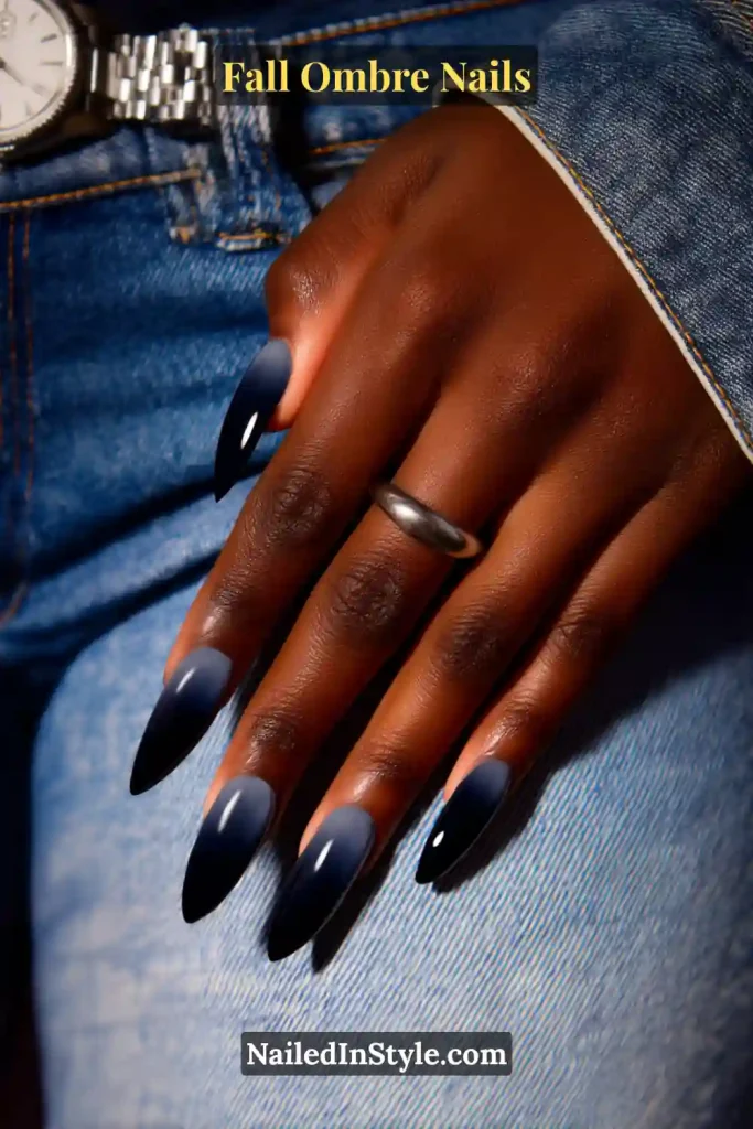 Fall ombre nails fading from deep navy to black tips for a sleek nightfall effect, styled with denim cuff and silver watch.