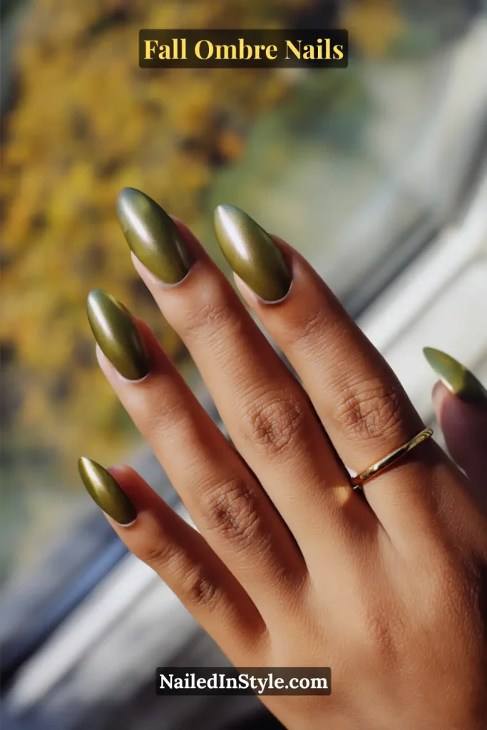Fall ombre nails in olive green with a luminous gold chrome halo effect, captured in soft window light.