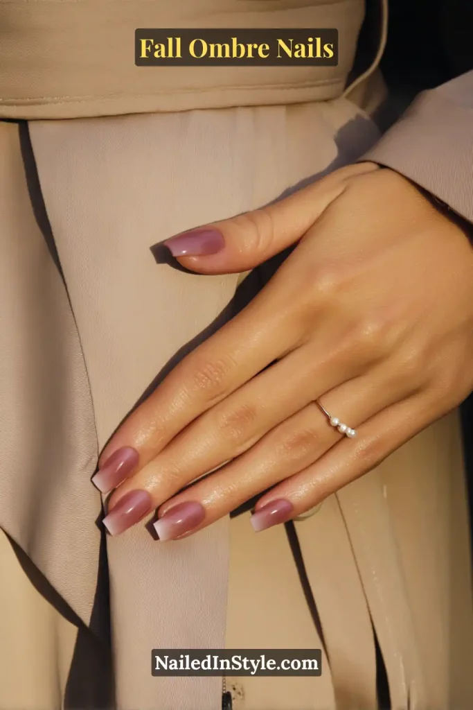 Fall ombre nails in rosewood blending into mauve blush, styled elegantly against a beige trench coat.