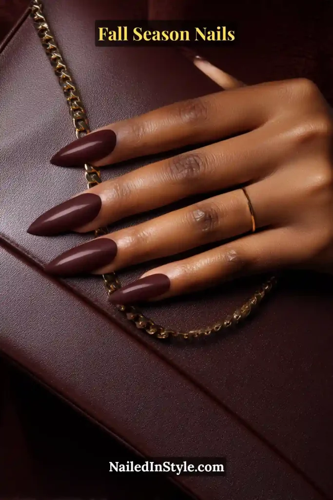 Matte mahogany nails with glossy crescent detail at the base, styled on a leather clutch.