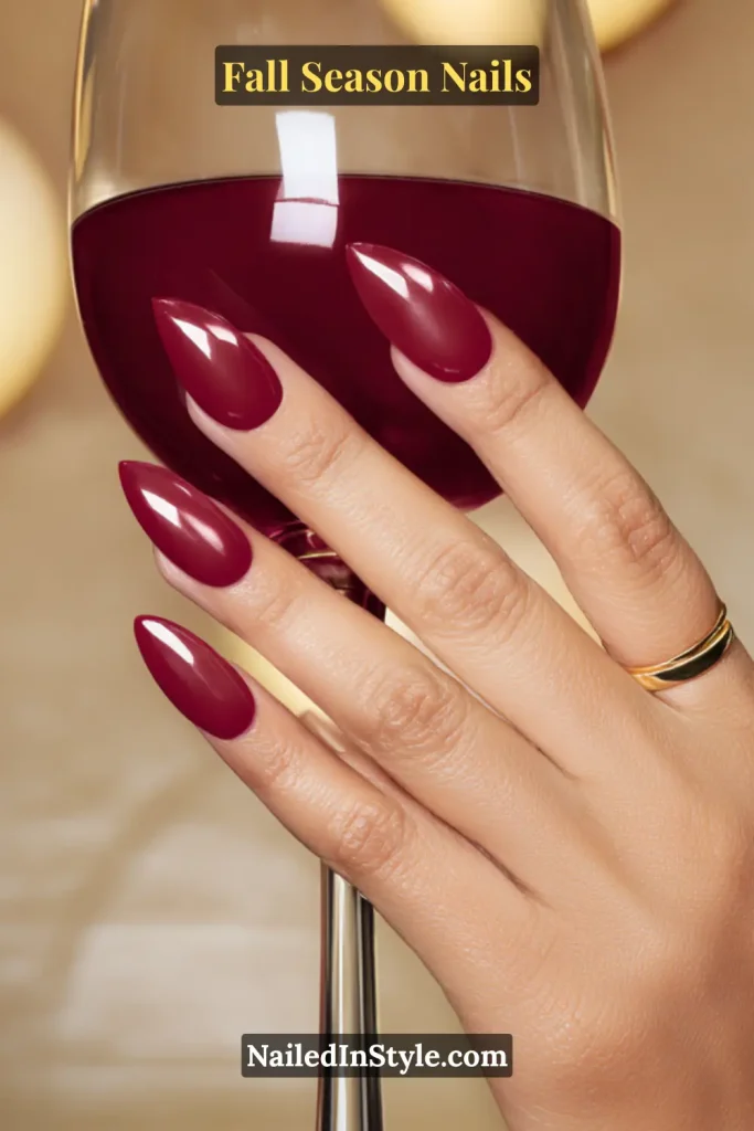 Jelly burgundy nails with stained-glass depth, styled holding a wine glass.