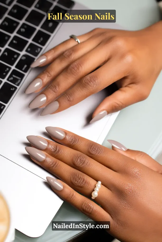 Neutral chrome nude nails with a polished finish, styled over a laptop with a cappuccino.