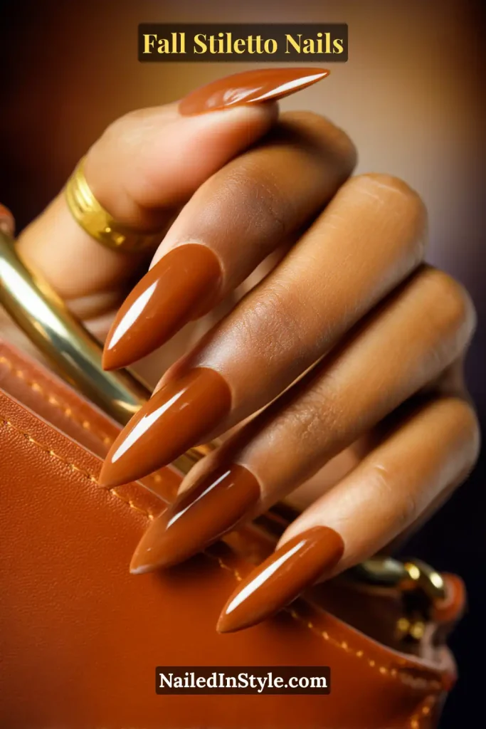 Glossy cognac stiletto nails styled with a leather handbag handle.