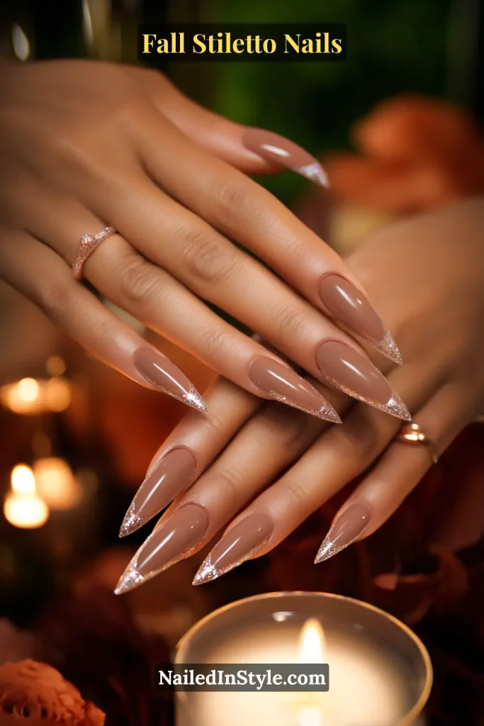 Iced mocha stiletto nails with glitter sugar-dusted tips, styled near a glowing candle.