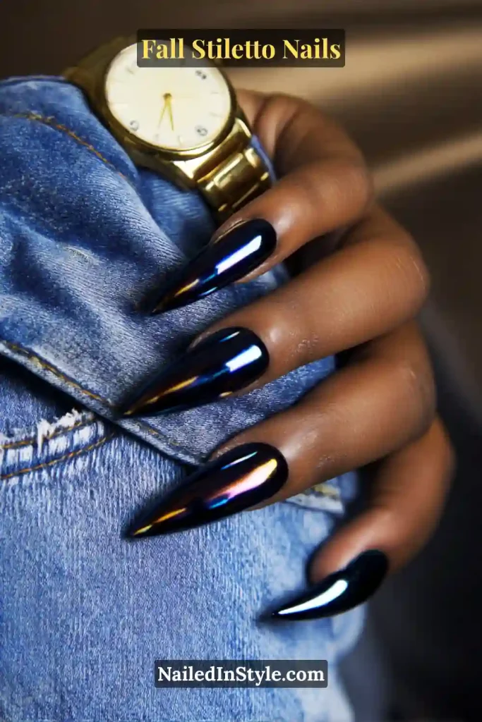 Navy-black chrome stiletto nails with shifting oil-slick effect, styled with denim cuff and gold watch.