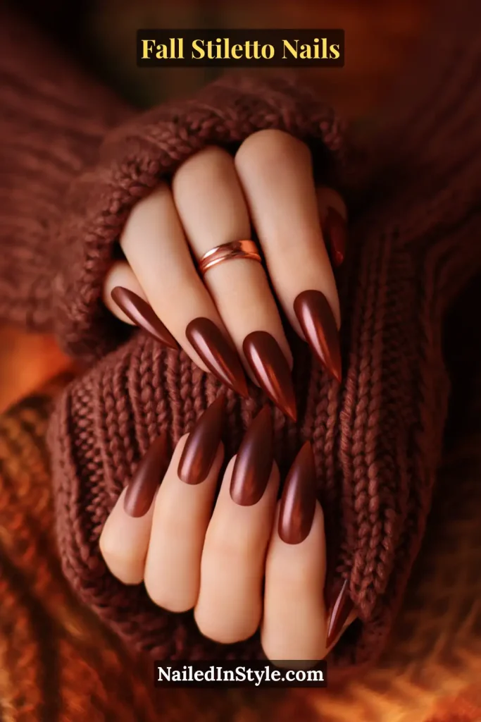 Matte truffle brown stiletto nails fading deeper at the tips, styled with a cable-knit sweater sleeve.
