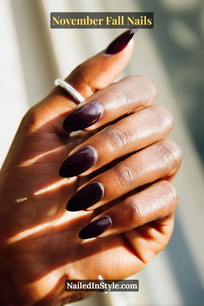 November fall nails in translucent blackberry jelly layers, glowing under backlit café light.