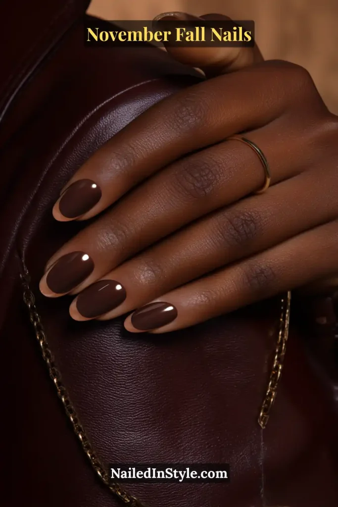 November fall nails in suede-matte mocha with a glossy outline, styled against a leather jacket sleeve.
