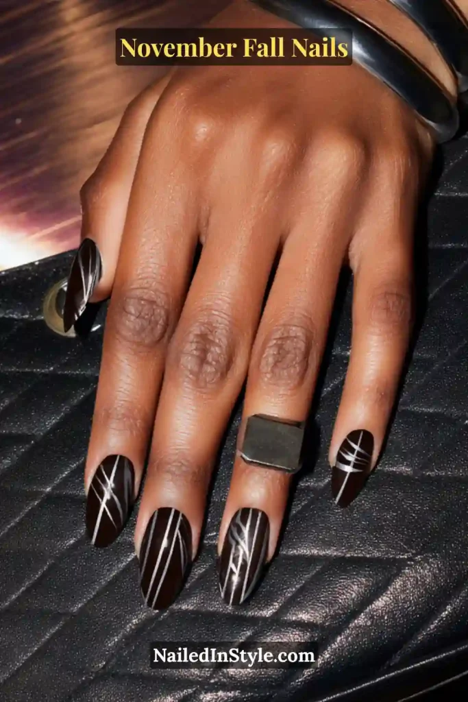 November fall nails in inky black with ultrathin pewter pinstripes, styled holding a structured mini bag.