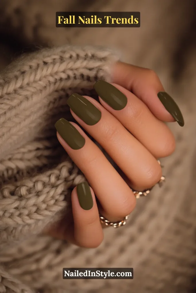 Fall olive green square nails with a glossy finish, styled against a chunky knit sweater for a modern seasonal aesthetic.