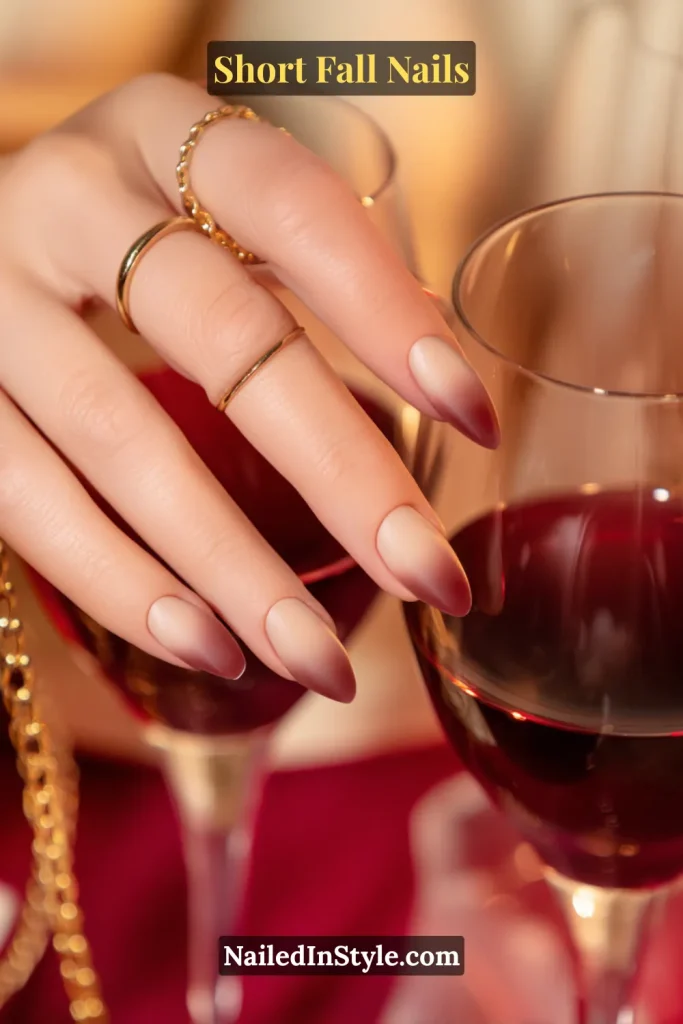 Short almond nails in a nude-to-fig ombre fade, soft and romantic, shown holding a wine glass.