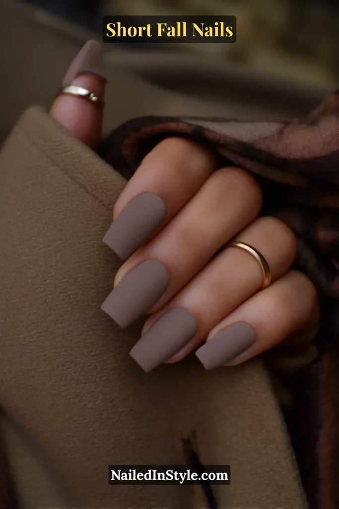 Short square nails in soft matte taupe, styled against a trench coat lapel for a chic autumn vibe.
