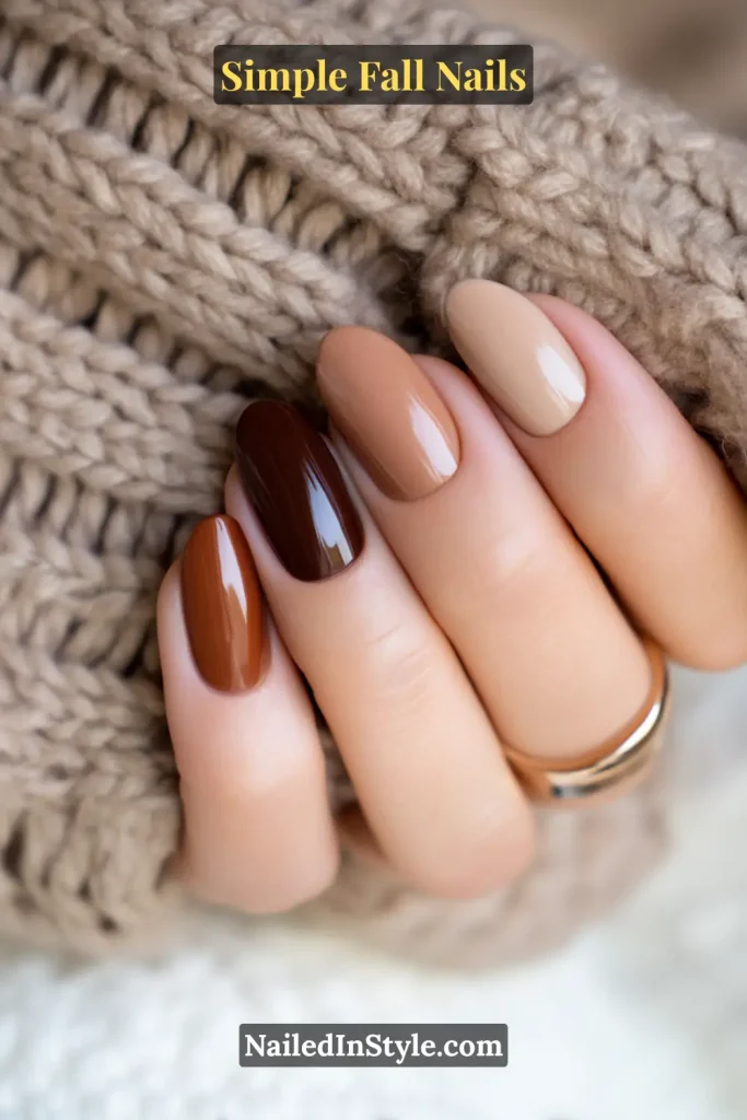 Simple fall nails with a tonal skittle design in five brown shades from latte beige to chestnut, styled against a cozy knit sleeve stack.