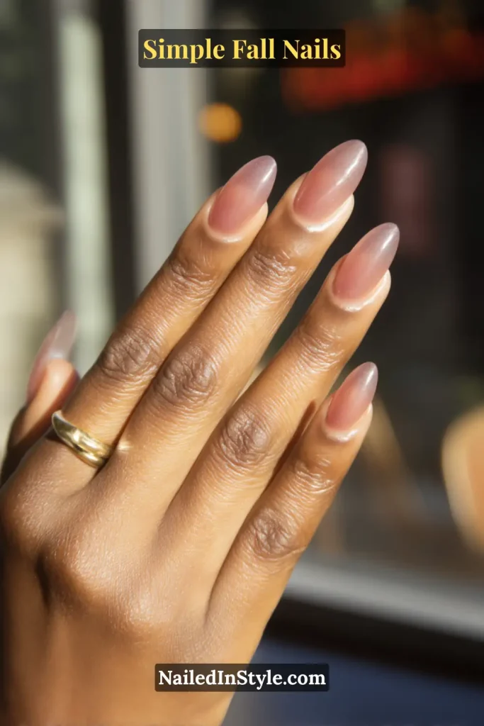 Simple fall nails with a cranberry sheer jelly tint, almond shape, glowing softly in backlit café window light; airy, translucent finish.