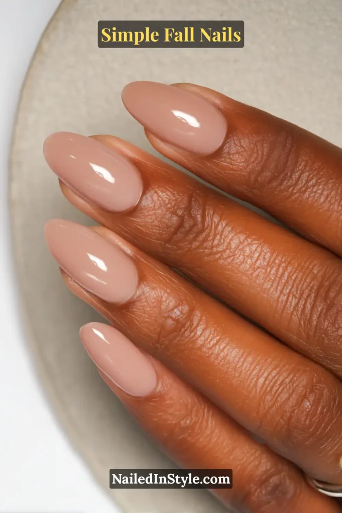 Simple fall nails in a milky latte nude jelly shade, almond shape, styled against a ceramic brunch plate; glossy one-and-done neutral.