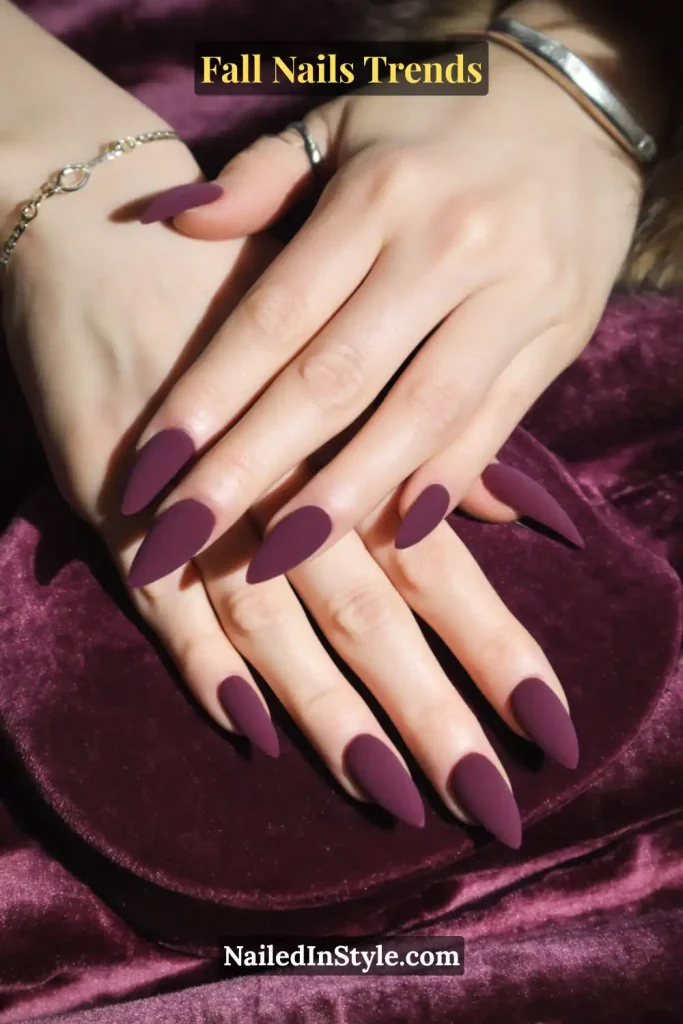 Fall Nails Trends Fall velvet plum almond nails in a soft matte finish, styled while resting gracefully on a rich velvet purse for cozy seasonal vibes.