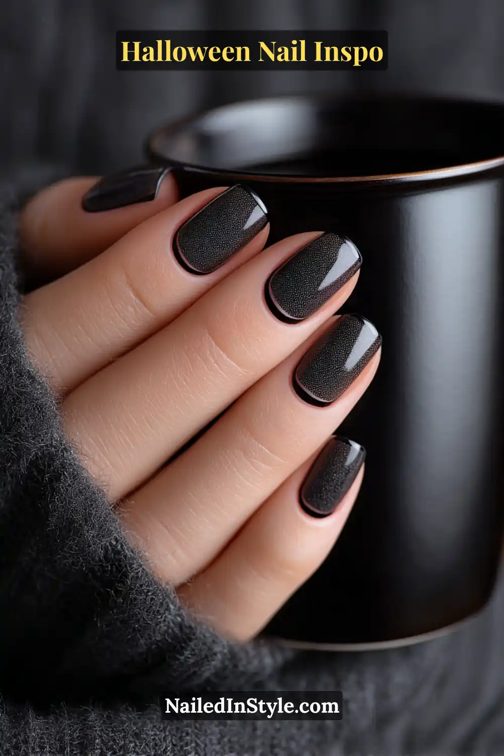 Short square nails in rich black velvet with a glossy micro-French tip, styled beside a matte black tumbler for a sleek, fashion-forward Halloween look.