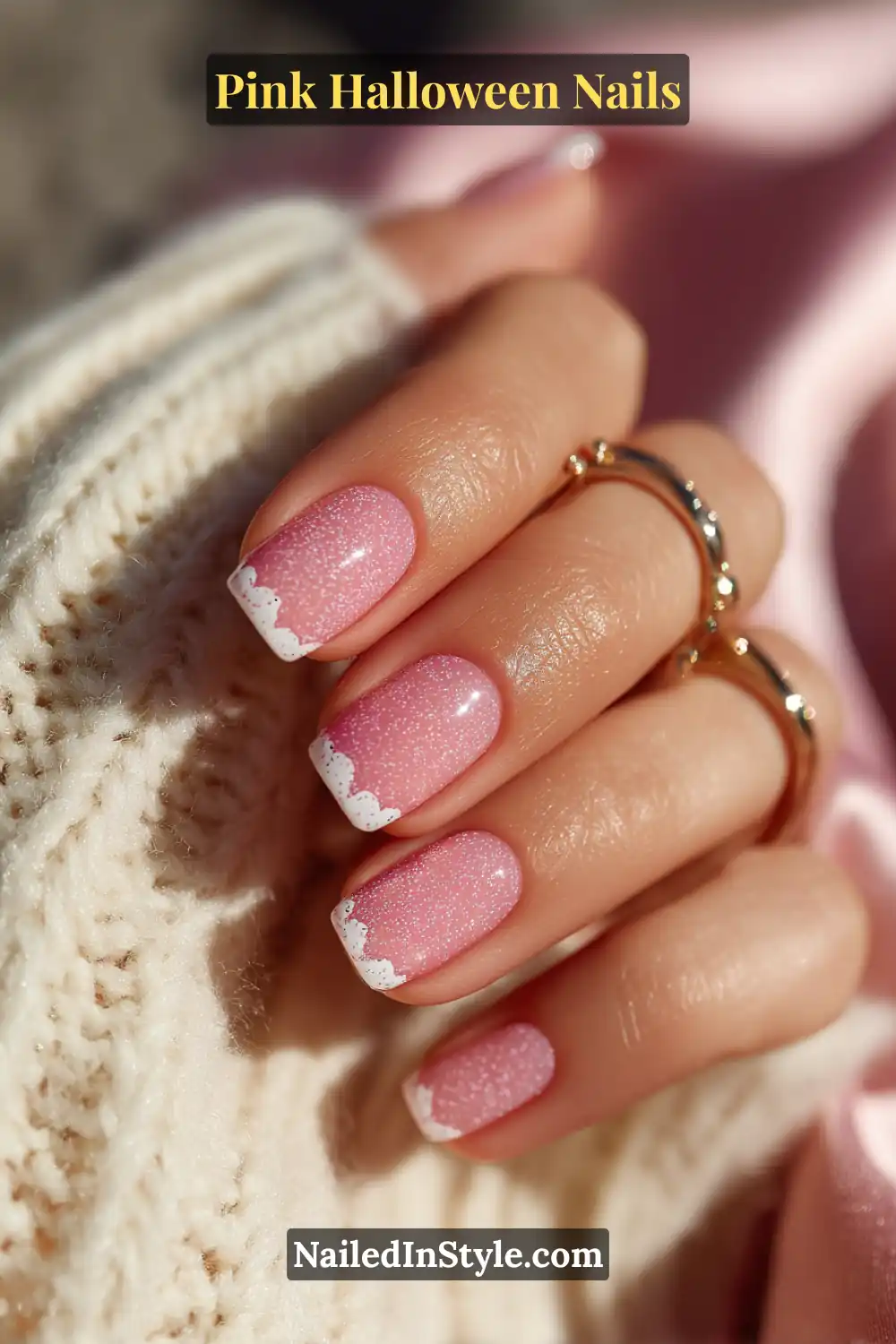 Pink Halloween nails with glossy bubblegum polish, tiny white ghost accent, and soft micro-French tips on short squoval nails, styled with silver hoops and a cream knit.