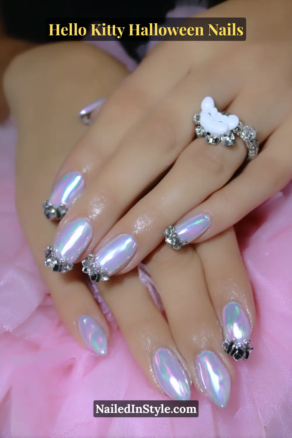 Medium almond nails glowing with a pastel chrome finish that shifts between lilac and cotton candy hues, topped with a glossy candy-like coating. Embellished with crystal accents for a dreamy Hello Kitty Halloween sparkle.