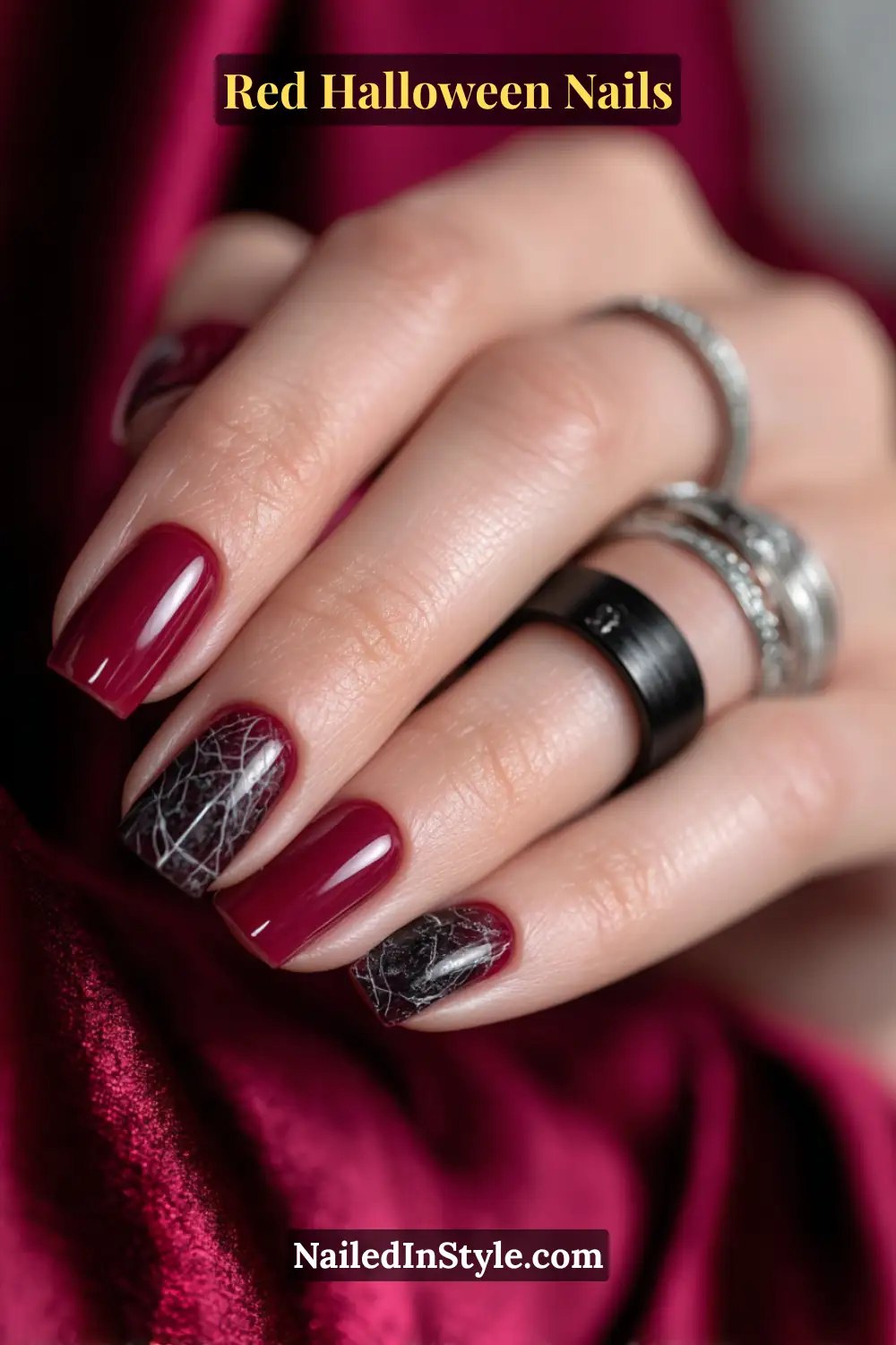 Medium squoval nails in deep cherry red with inky black web-like corner detailing over negative space; sleek, minimal, and architectural design; accented with matte black and silver rings; flattering on all skin tones.