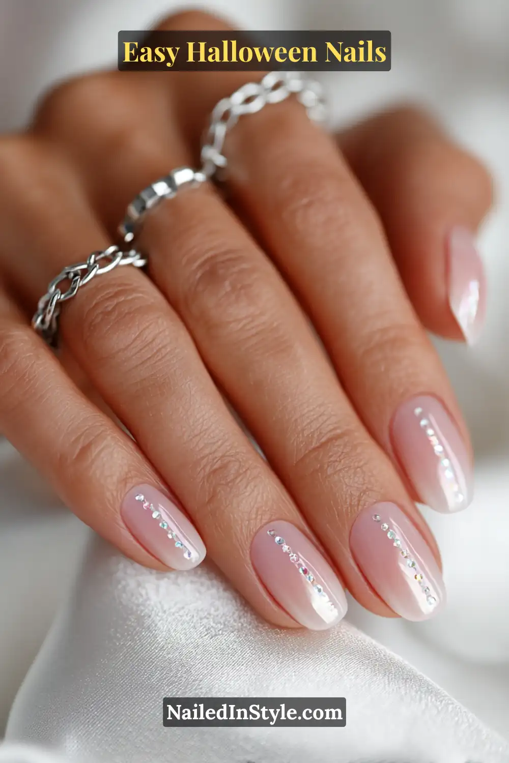 Short oval nails with glossy nude base and a straight vertical line of chrome micro dots, minimalist mirror detail for Easy Halloween Nails.