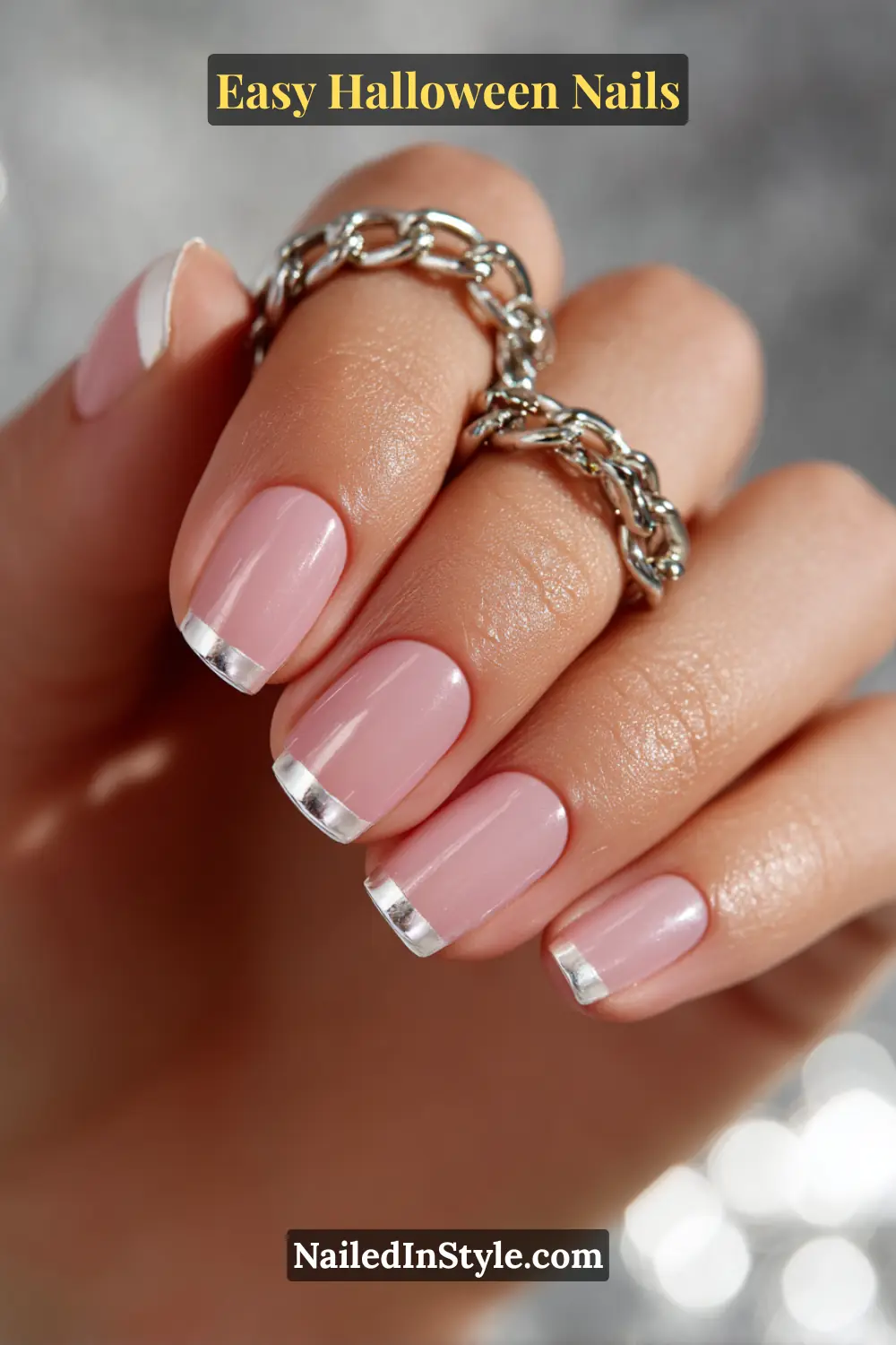 Easy Halloween Nails Squoval nails painted in a sheer pink base with slim silver chrome fang tips at the smile line, finished in a reflective mirror shine for Easy Halloween Nails.