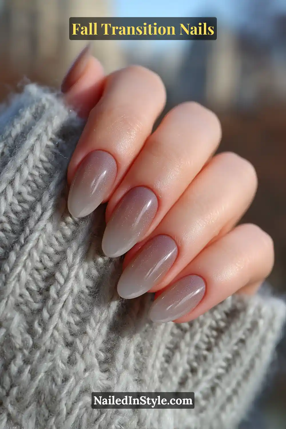 Medium almond nails with a soft ombré fade from milky quartz to smoky taupe, catching light gently against a cozy grey wool sweater.