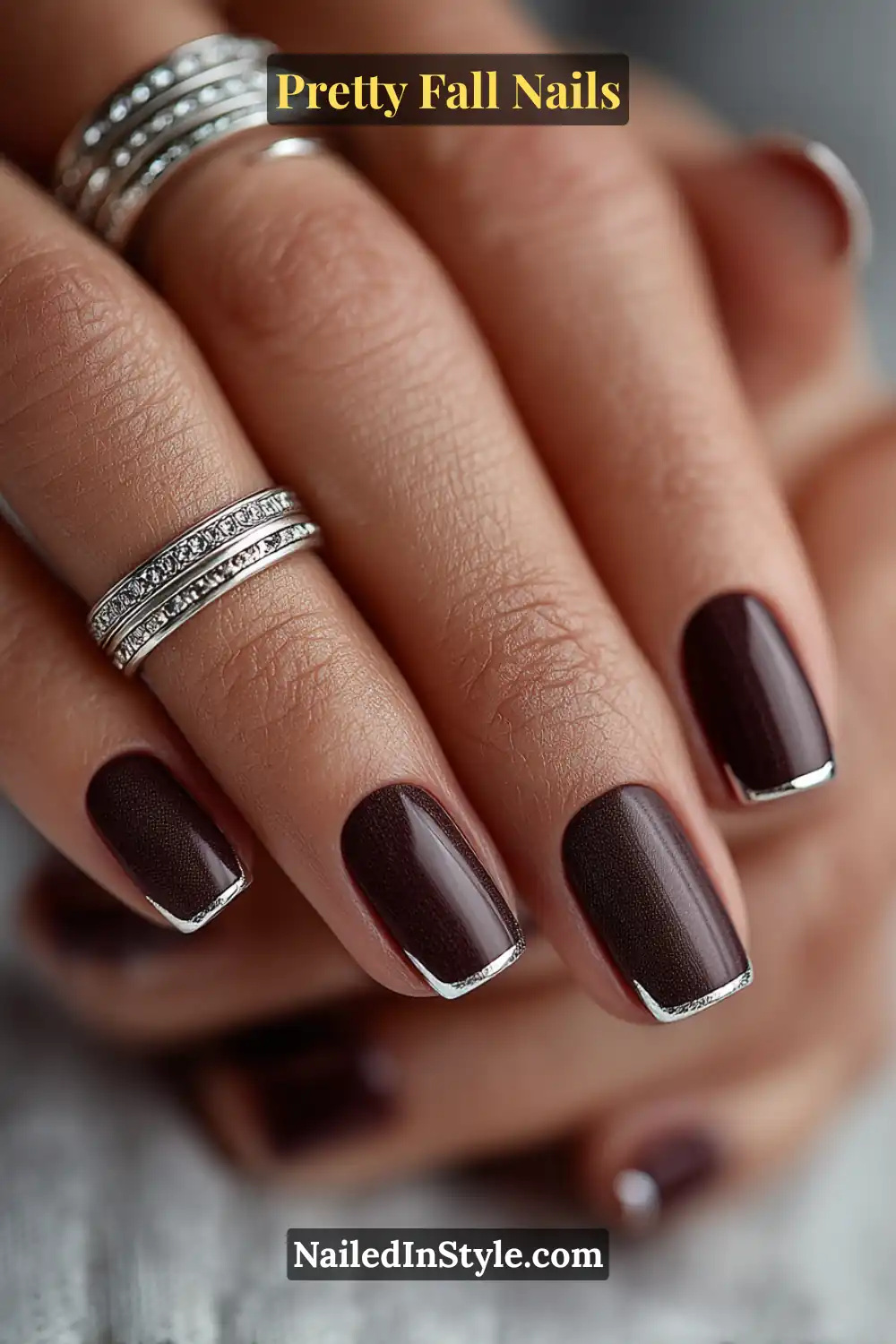 Short square nails in deep cocoa matte accented with sharp silver chrome corners, forming right-angle 3D edges that add a modern, architectural twist perfect for fall’s sleek style.