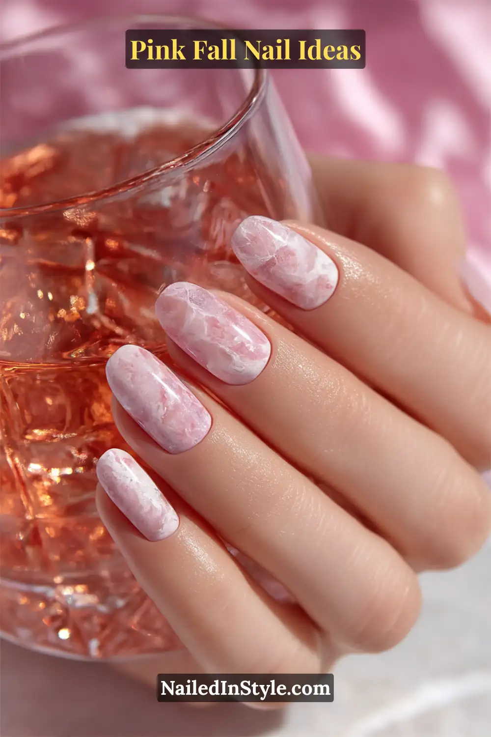 Pink Fall Nail Ideas: Chic, Fast & Photogenic 2025 4 Long almond nails in baby pink and lilac tones with soft marble veining and a satin top coat, glowing beside a rose-tinted glass tumbler.
