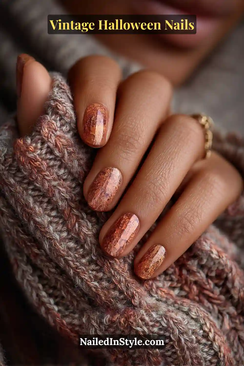 Short round nails with a warm ember-orange crackle glaze and glossy finish, creating a rustic, cozy vintage Halloween vibe against a knit sweater.