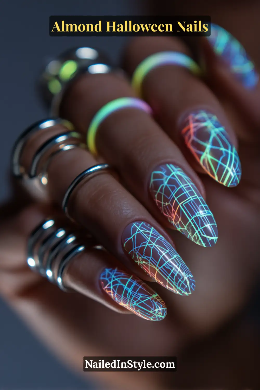 Close-up almond nails with neon web-like circuit lines and glowing dots in UV-reactive hues of blue, green, and orange on a translucent base, Almond Halloween Nails.