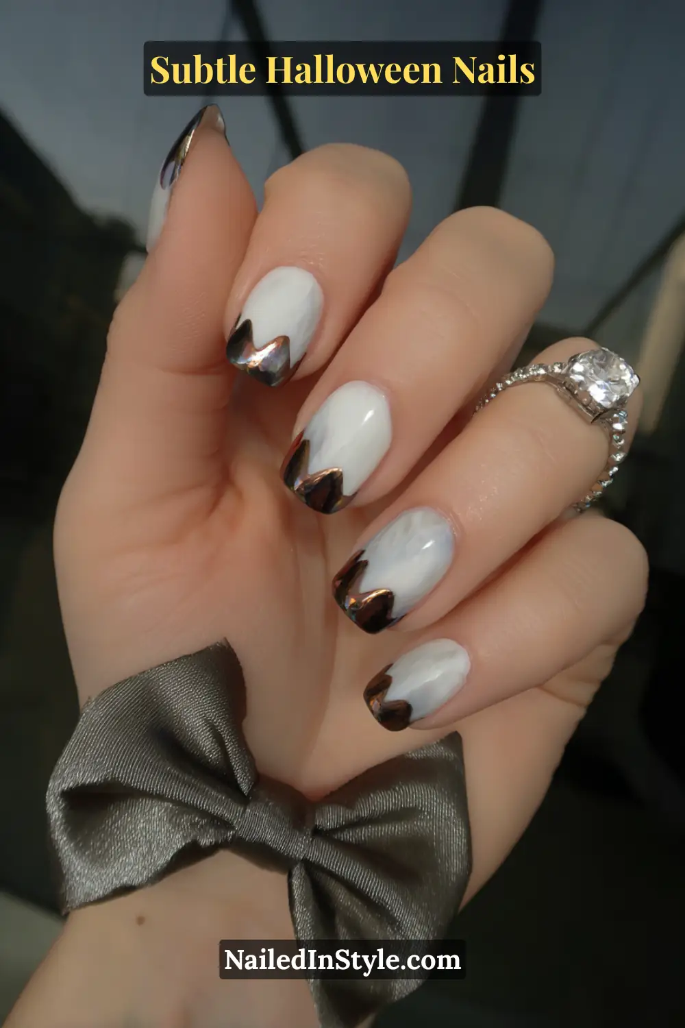 Medium oval nails blending soft dove-gray into luminous mirror-chrome tips, creating a seamless ombré effect that catches every flicker of light. Styled with a satin ribbon bow for a modern yet graceful Halloween finish.