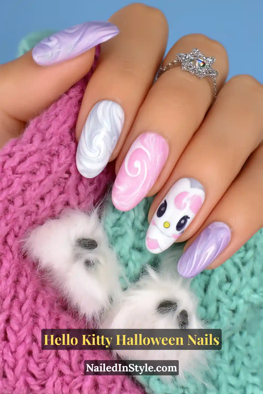 Short oval nails with pearlescent swirls of cotton white, baby pink, and lilac, featuring a soft Hello Kitty accent nail. Styled with a plush pastel scarf and cozy textures for a dreamy Halloween look.