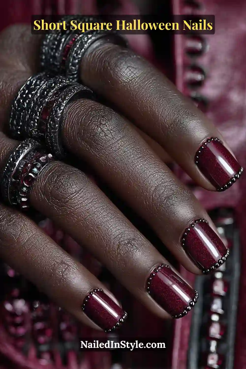 Short square deep garnet nails accented with a micro line of hematite studs near the cuticle, creating a bold gothic Halloween nail look.