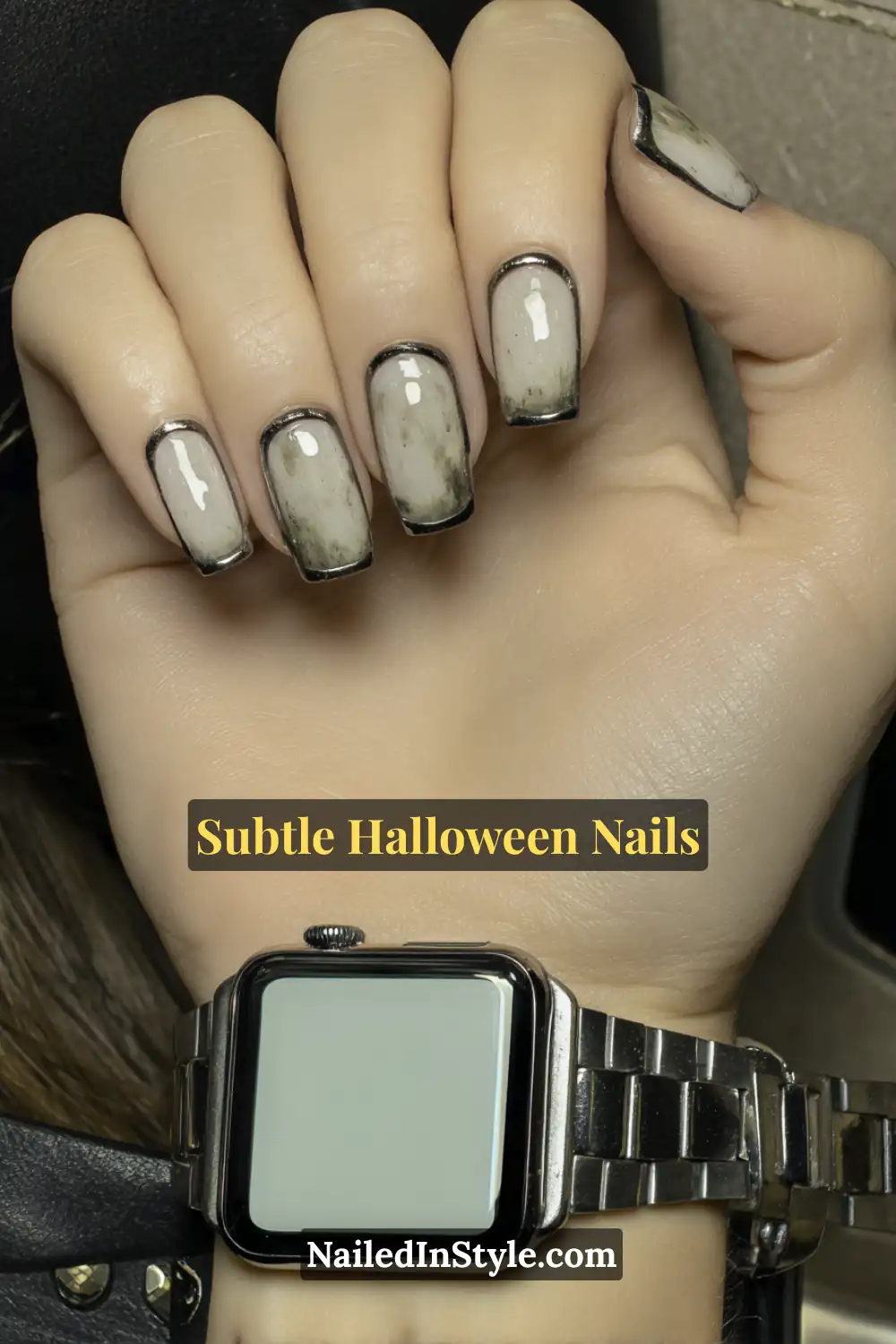 Short squoval nails featuring a sheer pearl base bordered by thin graphite outlines, creating a sleek negative-space frame with a smoky undertone. Styled with a chrome watch for a refined, contemporary Halloween aesthetic.