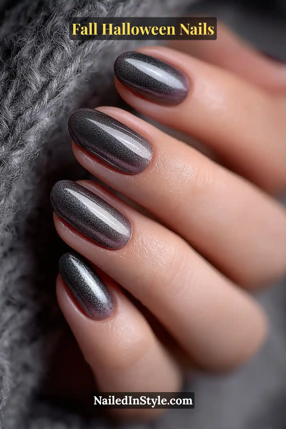 Short round nails in graphite and lilac tones with a soft metallic fade flowing from cuticle to tip, styled against a gray knit for a sleek, minimalist Halloween vibe.