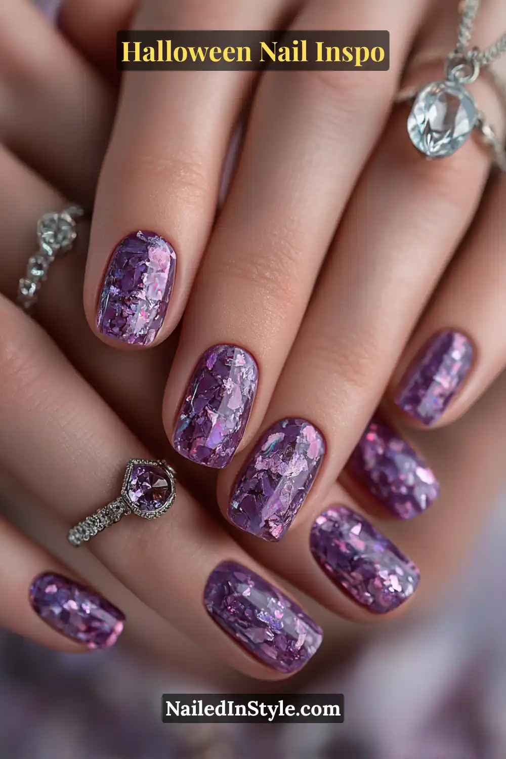 Short squoval nails in shimmering indigo with violet smoke and silver foil shards, creating a reflective 3D firefly effect for a cool Halloween vibe.