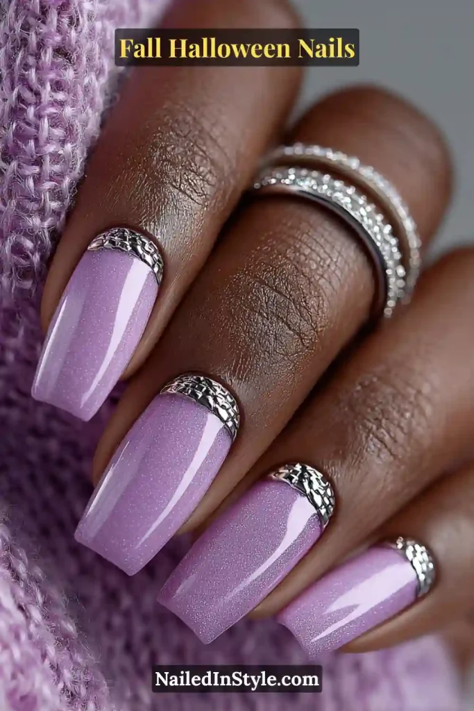 Medium square nails in soft lilac with gleaming silver chrome cuffs, styled against a cozy knit sweater and adorned with stacked silver rings for a polished 3D accent look.