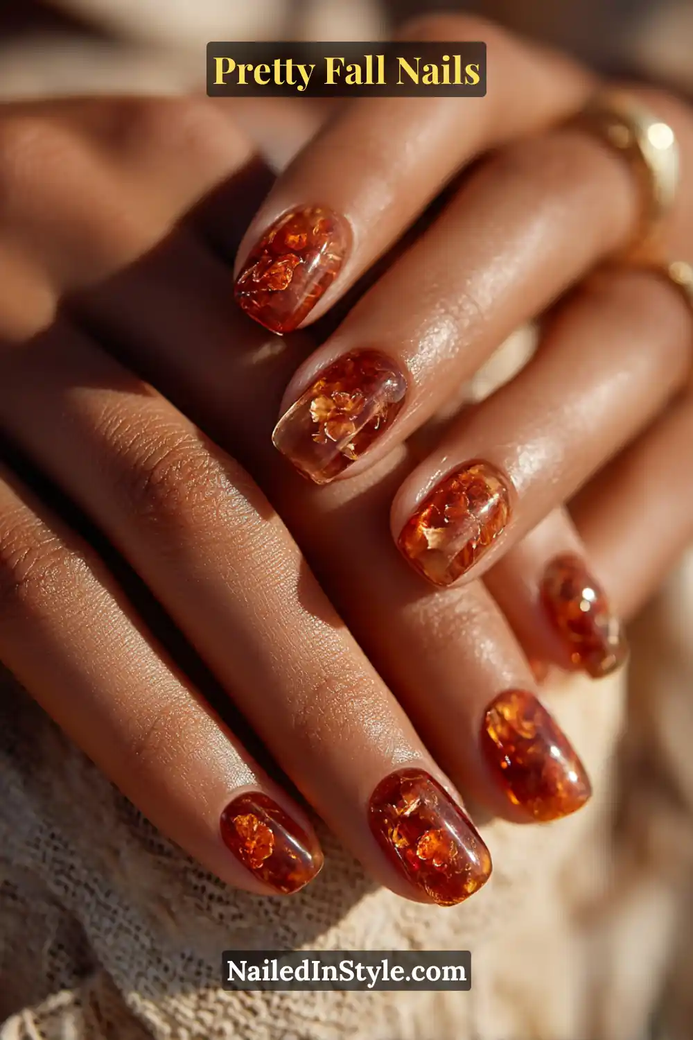 Short squoval nails coated in translucent maple and amber tones with 3D syrupy drips that catch the light like molten glass, radiating golden warmth against deeper autumn skin.