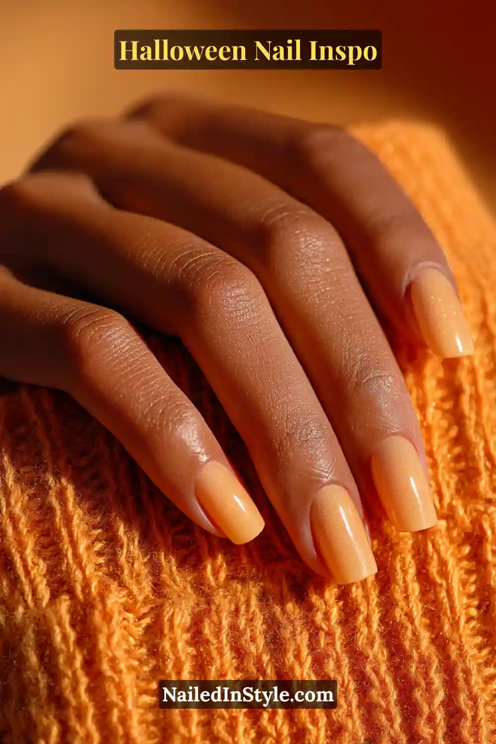 Halloween Nail Inspo Medium almond nails painted in a sheer marigold base with soft smoky ribbons, glowing beautifully in golden-hour light against a cozy knit sleeve.
