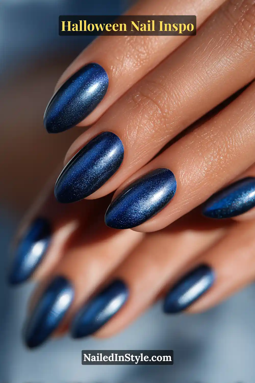 Medium oval nails in deep midnight navy with a magnetic silver cat-eye beam shimmering across the center, glowing like moonlight on a clear Halloween night.