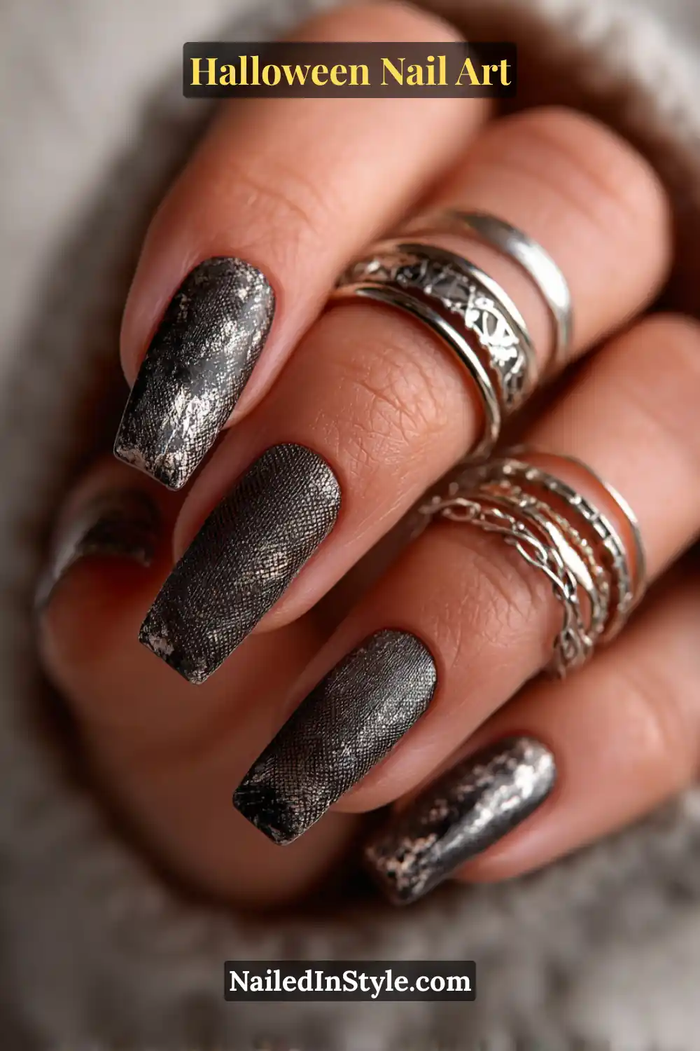 Long coffin nails in smoky graphite and pearl tones with a delicate metallic mesh overlay, paired with layered silver rings for a sleek, celestial Halloween look.