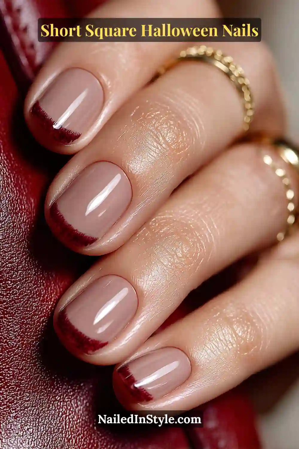 Short square nails with a thin mulled berry crescent tip over a nude base, creating a refined and cozy Halloween nail style.