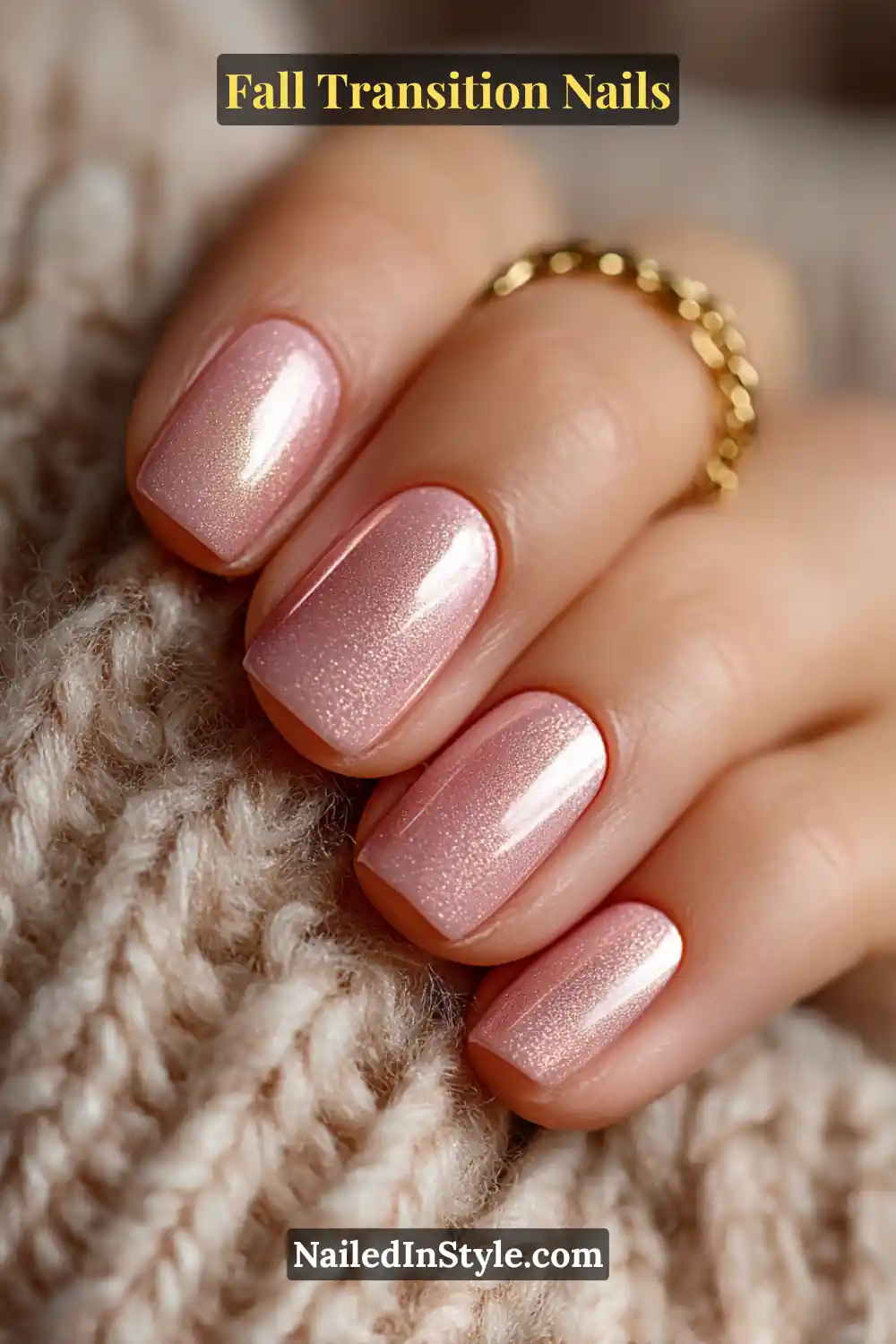 Short round nails in sheer petal pink layered with a brushed bronze overlay and pearl shimmer, styled beside a cozy knit and gold chain.