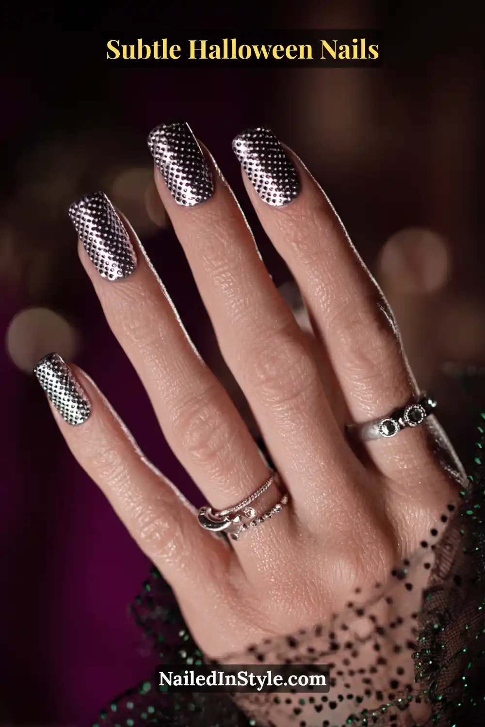 Short squoval nails covered in a pewter-silver base with scattered chrome pin-dots and embedded micro crystals, creating a jewelry-like sparkle that shifts under light. Styled with silver hoop accessories for a futuristic Halloween edge.