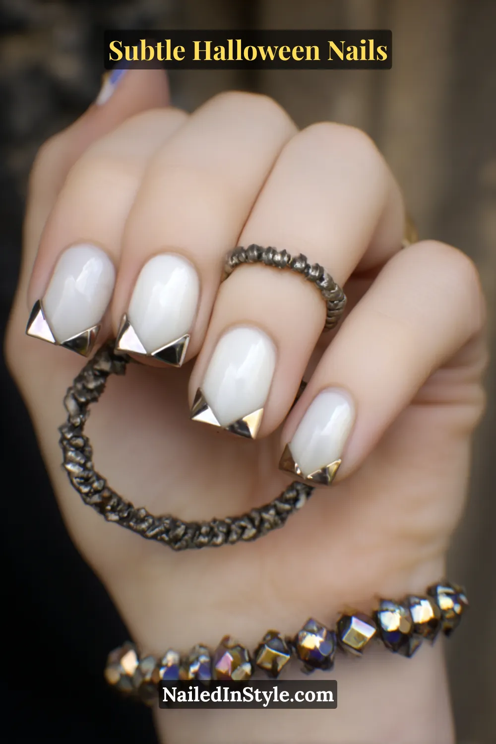 Short square nails with a soft matte porcelain base, accented by 3D chrome corners for a clean geometric contrast. Paired with a stainless bangle and metallic jewelry for a minimalist yet striking Halloween statement.